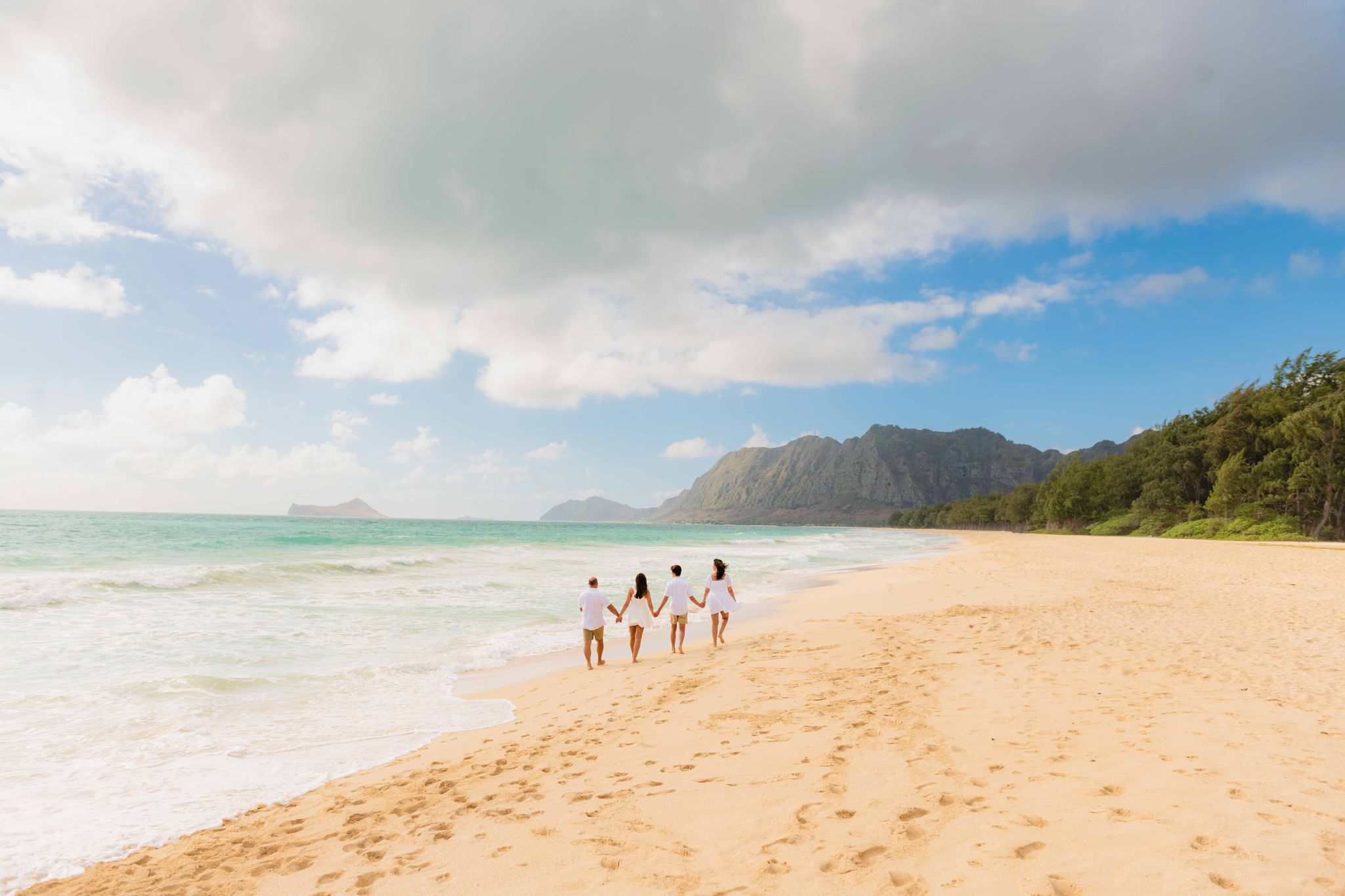 An image of 4 friends on the beach holding hands captured by oahu hawaii photographers