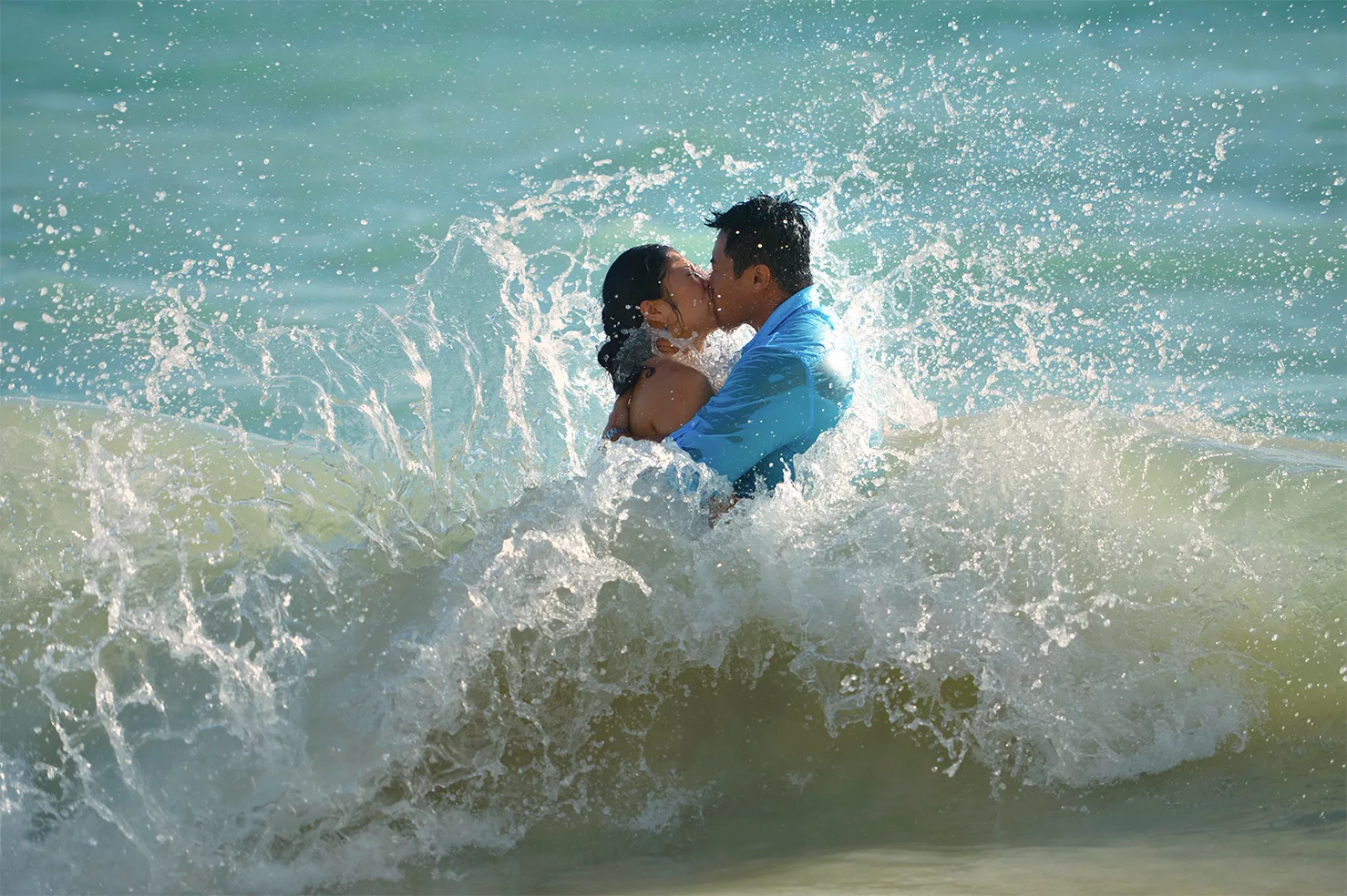 An image of a couple kissing on the beach captured by oahu hawaii photographers