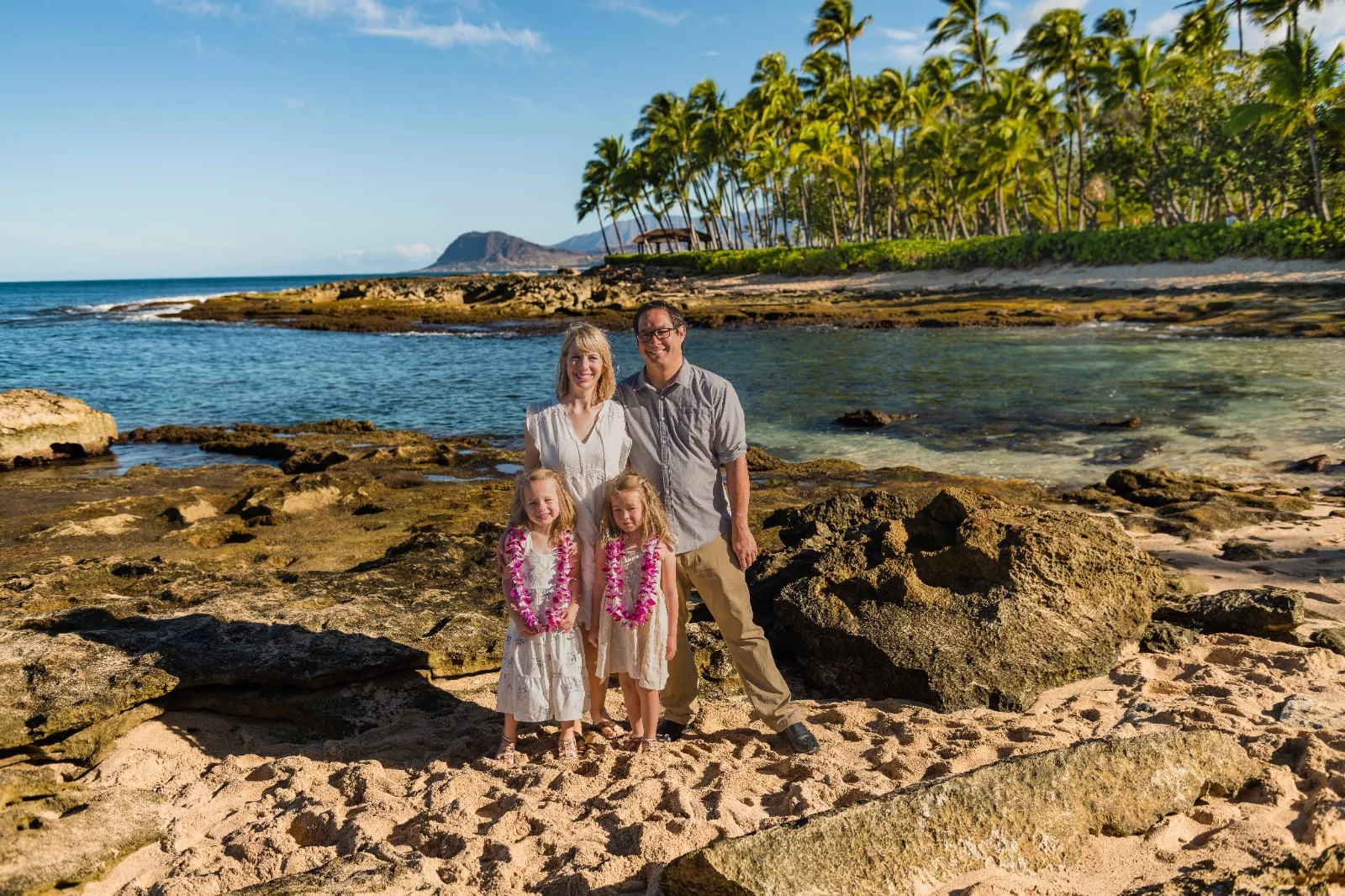 an image of a family of 4 all smiling with the beach as their background captured by koolina photographer