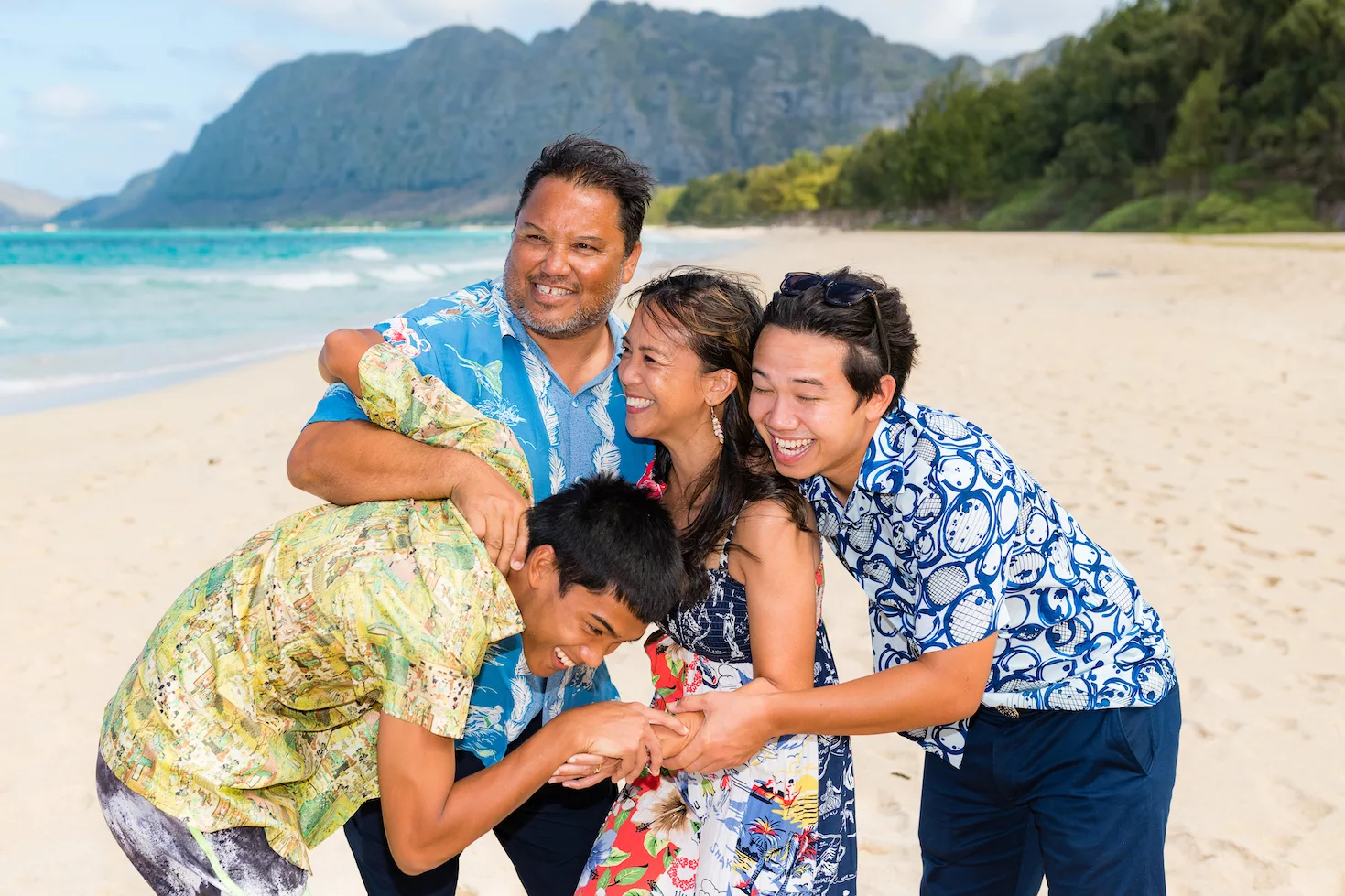 A family of four laughing together at the beach taken by Oahu hawaii photographer