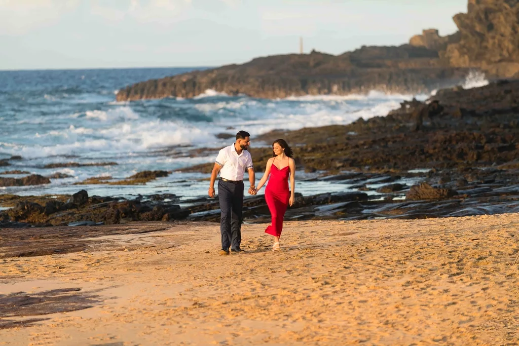 an image of a couple happily walking at the beach smiling at each other taken by oahu hawaii photographers