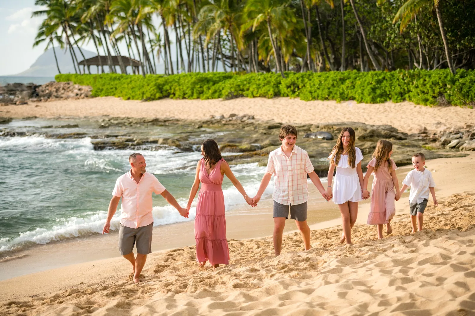 an image of a family of 6 walking hand in hand at the beach taken by a koolina photographer