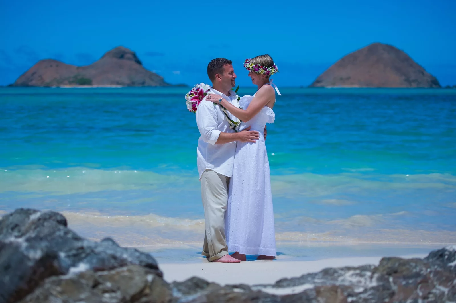 an image of a man and woman in the beach facing and holding each other taken by oahu photographer