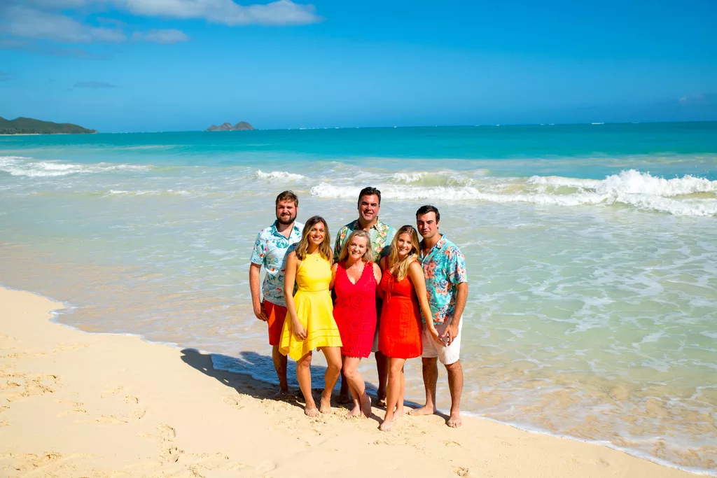 An image of a family at the beach smiling in front of a camera for their family photoshoot by oahu photographers