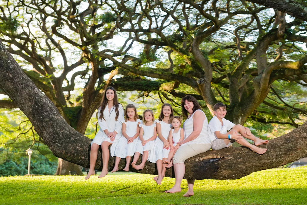an image of a mom and her 6 children sitting on a tree branch taken by oahu photographer