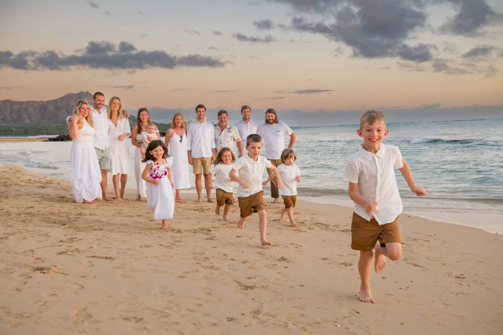 an image of a big family at the beach with a boy who's running towards the camera taken by waikiki family photographer